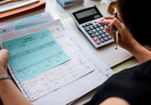 Persona revisando facturas y calculando gastos, representando el impacto de una deuda y la organización financiera.